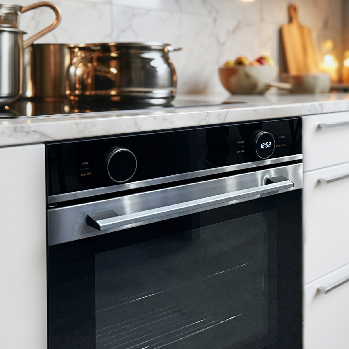 Heinner inbouwoven met stalen handgreep in keuken naast kookplaat en marmeren werkblad met keukenbenodigdheden